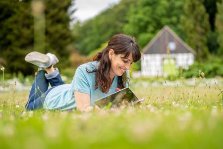 Frau liegt auf dem Rasen im Botanischer Garten Bielefeld und liest