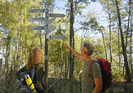 Zwei Personen vor Wanderwegweiser