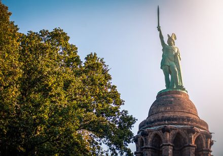 Das Hermannsdenkmal oberhalb von Dermold in der Halbtotale mit Baum daneben