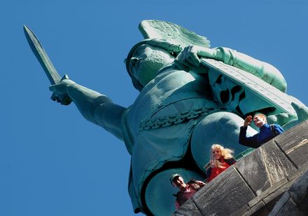 Blick von unten auf das Detmolder Hermannsdenkmal mit drei Besuchern. Teutoburger Wald.Foto: Teutoburger Wald Tourismus, Michael Muench