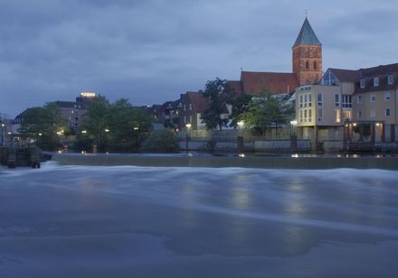 Das Emswehr in Rheine mit der Innenstadt im Hinergrund in der Dämmerung